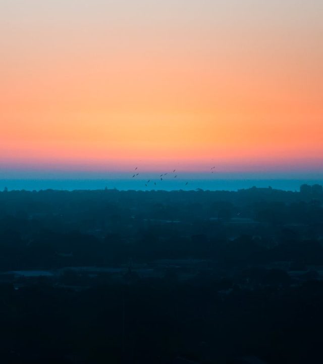 Stunning view of Adelaide city skyline with a vivid sunrise, showcasing a tranquil morning atmosphere.
